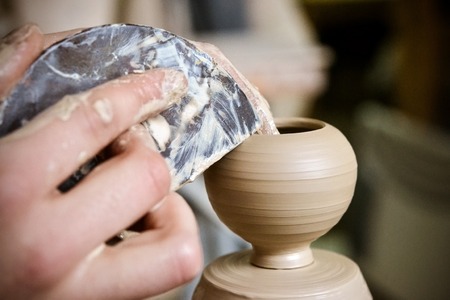 Potter makes a pretty small vase from clay, using the tool for surface leveling close-up macro. Space for text.の写真素材