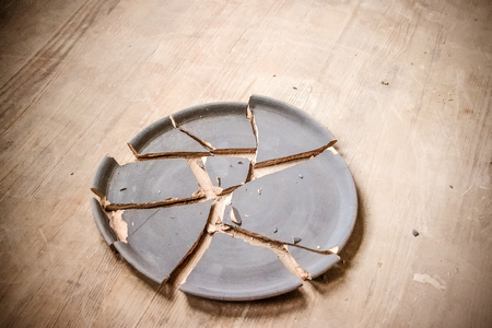 broken clay plate lying on a wooden tableの写真素材