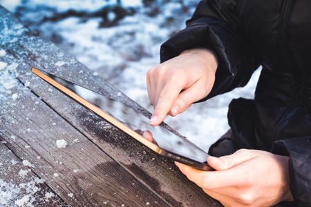 man flips through photos on a tablet while sitting at a wooden tableの写真素材