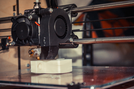 3d printer printing black flat shapes on a dark background close-up. Image of automatic three...
