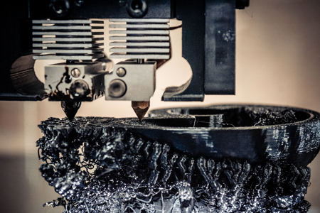 3d printer printing black shapes close-up. Image of automatic three dimensional 3d printer performs...