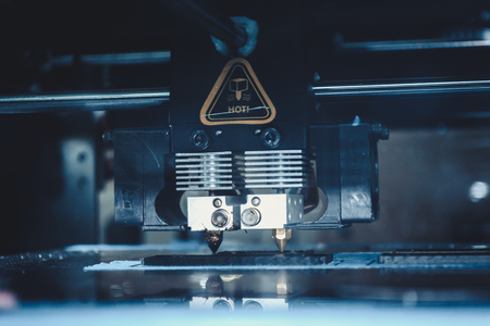 3d printer printing black flat shapes on a dark background close-up. Image of automatic three dimensional 3d printer performs plastic modeling in laboratory.の写真素材