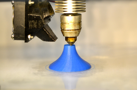 Modern 3D printer printing figure close-up macro.Automatic three dimensional 3d printer performs plastic blue colors modeling in laboratory. 3d-printing processing with white backgroundの写真素材