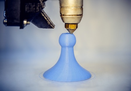 Modern 3D printer printing figure close-up macro.Automatic three dimensional 3d printer performs plastic blue colors modeling in laboratory. 3d-printing processing with white backgroundの写真素材