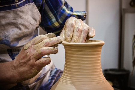 The potter molds clay jug pot closeup. Workshop on sculpt white clay closeup. Dirty hands in the clay. Making ceramic products . Artistic creative.の写真素材