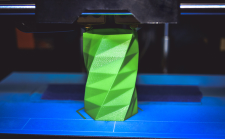3D printer works and creates an object from the hot molten plastic close-up. Automatic three dimensional 3d printer performs plastic green colors modeling in laboratory.の写真素材