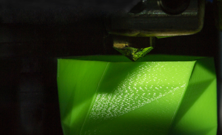 3D printer works and creates an object from the hot molten plastic close-up. Automatic three dimensional 3d printer performs plastic green colors modeling in laboratory.の写真素材