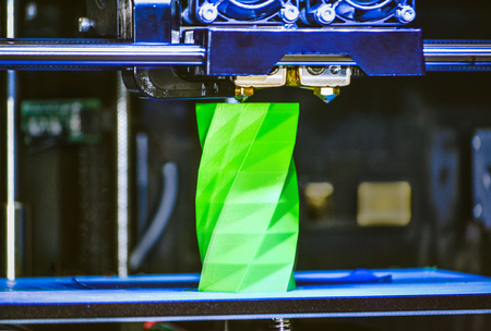 3D printer works and creates an object from the hot molten plastic close-up. Automatic three dimensional 3d printer performs plastic green colors modeling in laboratory.の写真素材