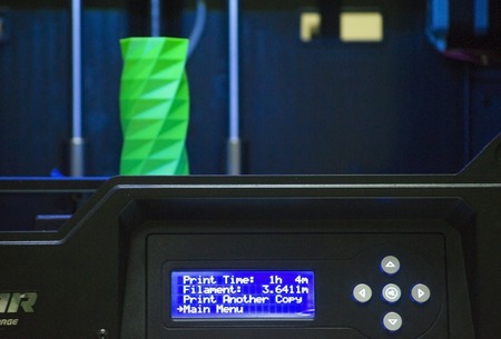 The object printed 3D printer on a blue and black background in the 3D printer. Automatic three dimensional 3d printer performs plastic green colors modeling in laboratory.の写真素材