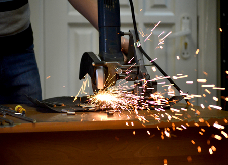 Worker man cutting a metal pipe in two pieces and lot of sparks flying straight into the camera...