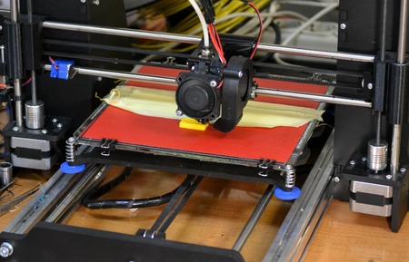 Modern 3D printer printing figure close-up. Automatic three dimensional 3d printer performs plastic yellow colors modeling in laboratory. Progressive modern additive technologyの写真素材