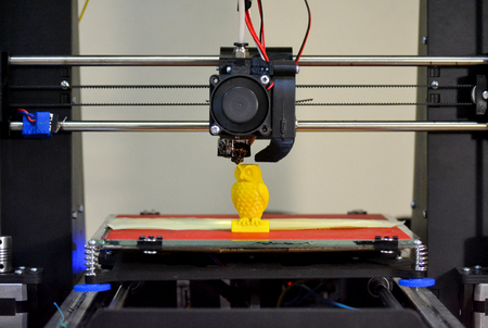 Modern 3D printer printing figure close-up. Automatic three dimensional 3d printer performs plastic yellow colors modeling in laboratory. Progressive modern additive technologyの写真素材