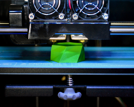 3D printer works and creates an object from the hot molten plastic close-up. Automatic three dimensional 3d printer performs plastic green colors modeling in laboratory.の写真素材