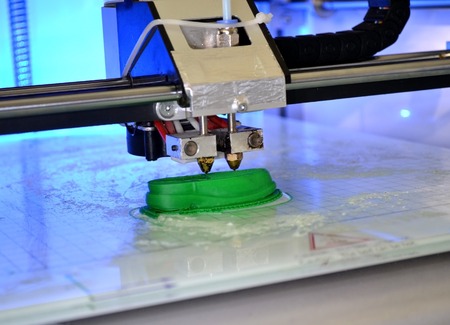 3D printer prints the form of molten plastic green close-up. Automatic three dimensional 3d printer performs plastic modeling in laboratory. Progressive modern additive technologyの写真素材