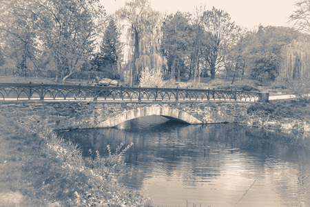 Vintage photo park with an ancient bridge across the lake pondの写真素材