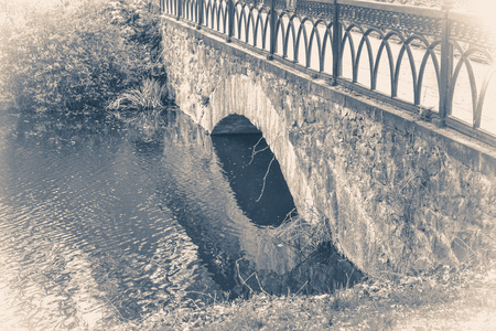 Vintage photo park with an ancient bridge across the lake pondの写真素材