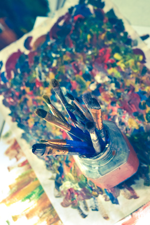 Brushes for drawing stand in a glass with a bristle upwards in a picture from smears with oil paints.の写真素材