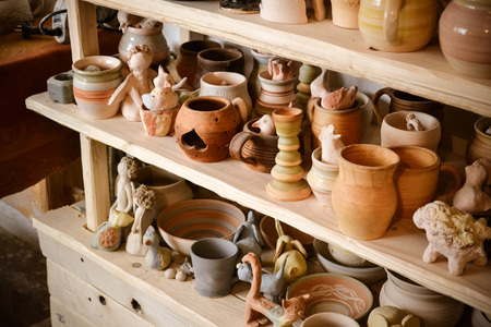 Wooden racks in a pottery workshop in which there are pottery, many different pottery standing on the shelves in a potery workshop. Low lightの写真素材