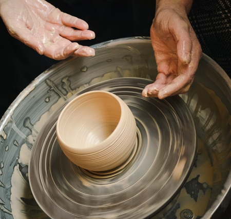 Hands of the master potter and vase of clay on the potter's wheel close-up. Master crock. Twisted potter's wheel.の写真素材