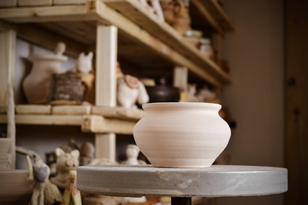 Clay pot close-up in the foreground and shelves with pottery - on the secondの写真素材