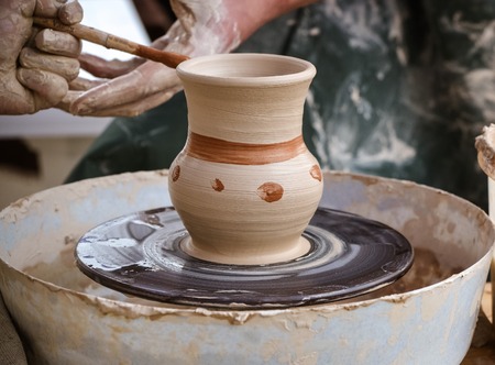 Creating vase of white clay close-up. The sculptor in the workshop makes a jug out of earthenware...