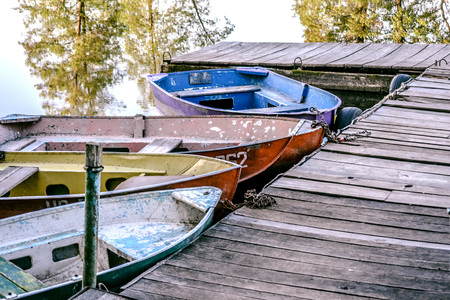 Old iron frayed and shabby boat tied to wooden dock close-upの写真素材