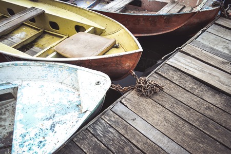 Old iron frayed and shabby boat noses tied to wooden dock close-up