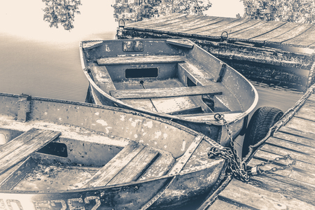 Old vintage photo. A few old simple boats on the wooden pierの写真素材