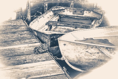 Old vintage photo. A few old simple boats on the wooden pierの写真素材