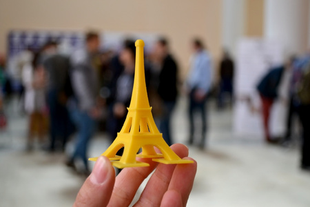 The model is yellow printed on a 3d printer on hand close-up. On the back of a blurry plan - people. Progressive modern additive technology. Copy spaseの写真素材