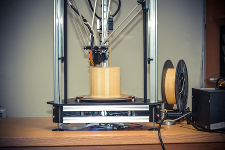 Modern 3D printer printing figure close-up. Copy space. Automatic three dimensional 3d printer performs plastic yellow colors modeling in laboratory. Progressive modern additive technology. Filter.の写真素材