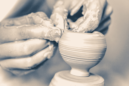 Girl sculpts in clay pot closeup. Modeling clay close-up. Caucasian man making vessel daytime of white clay in fast moving circle. Art, creativity. Ukraine, cultural traditions. Hobbiesの写真素材