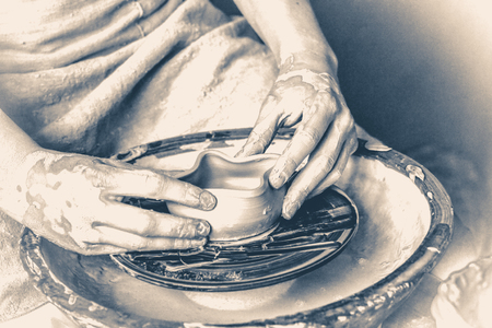 person potter makes clay earthen pot on a potters wheel in pottery workshopの写真素材