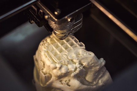 3D printer prints the form of molten plastic white close-up. Automatic three dimensional 3d printer performs plastic modeling in laboratory. Progressive modern additive technologyの写真素材