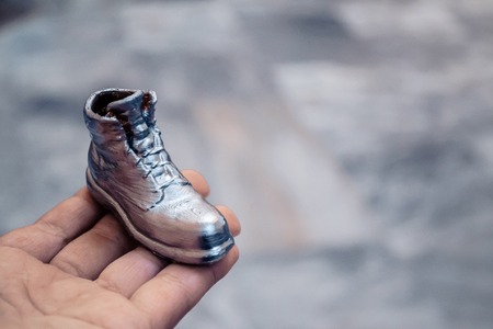 Object in the form of a boot printed on a 3d printer and covered with enamel on hand close-up. Isolated on white background. Progressive modern additive technology. Copy spaseの写真素材
