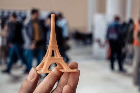 The model is yellow printed on a 3d printer on hand close-up. On the back of a blurry plan - people. Progressive modern additive technology. Copy spaseの写真素材