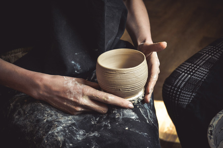 A raw clay pot in the hands of a potter. Master crock.の写真素材