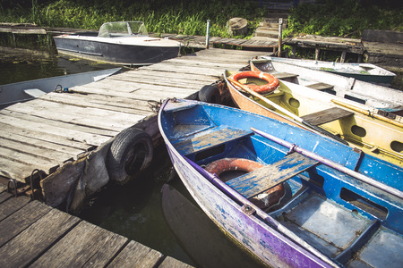 Old iron frayed and shabby boat noses tied to wooden dock close-upの写真素材