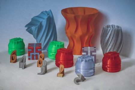 Models printed by 3d printer. Bright colorful objects printed on 3d printer on table.Automatic three...