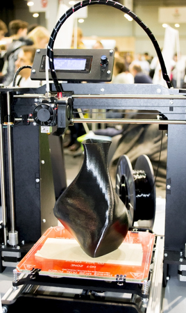 3D printer printing a model in the form of black vase close-up. The concept modern additive...