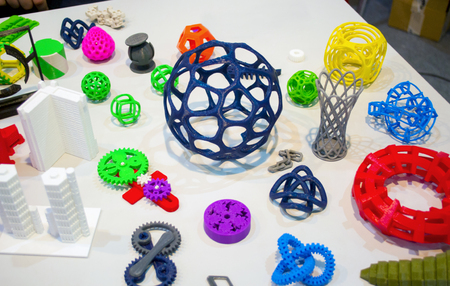 Abstract models printed by 3d printer close-up. Bright colorful objects printed on a 3d printer on a white table. Progressive modern additive technology. Concept of 4.0 industrial revolution