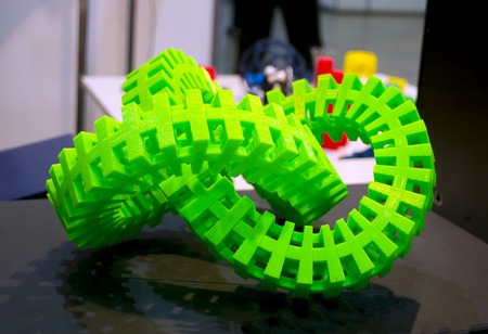 Big abstract object of green color printed on a 3d printer on a white table. Fused deposition modeling, FDM. Progressive modern additive technology. Concept of 4.0 industrial revolutionの写真素材