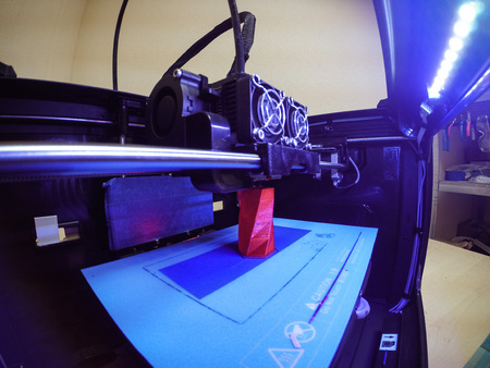3D printer prints the form of molten plastic red close-up. Automatic three dimensional 3d printer performs plastic modeling in laboratory. Progressive modern additive technologyの写真素材