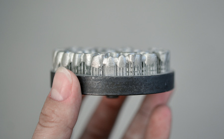 Object printed on metal 3d printer. Dental crowns created in a laser sintering machine close-up....