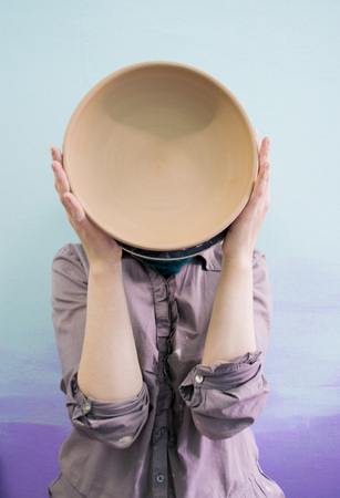 Master Potter holds round clay plate in his hands.Potters body. Sculptor sculpts pots products from white clay. Workshop pottery. Master crock. Creativity. Cultural traditions. Handmade. Craftの写真素材
