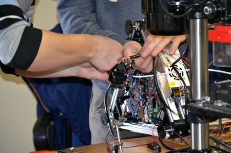 Two male masters work in the workshop with electronics, wires, 3d printer