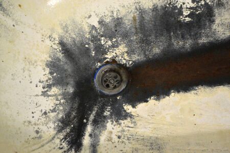 Very old rusty shabby bath close-up. A bath with peeling white enamel. Water flows in an old dirty bathtub. Black rusted dirty bath. Drain water in the rusty bathroom.の写真素材