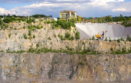 yellow machine stonecutter stands with plenty of macadam in a quarry in which do a granite