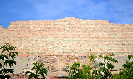wall of red brick shattered against the blue skyの写真素材