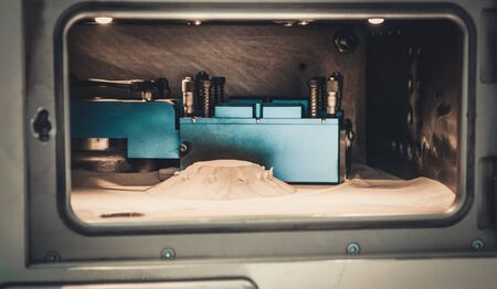 Object printed on metal 3d printer, laser sintering machine for metal close-up. A metal object sprinkled with metal powder after raising the platform into working chamber. DMLS, SLM, SLS technology.の写真素材